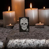 Lifestyle image of Anne Stokes Fancy Skull Lighter standing on cobblestone with lit candles in the background
