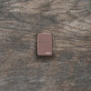 Lifestyle image of High Polish Rose Gold Zippo Logo laying flat on a wooden surface